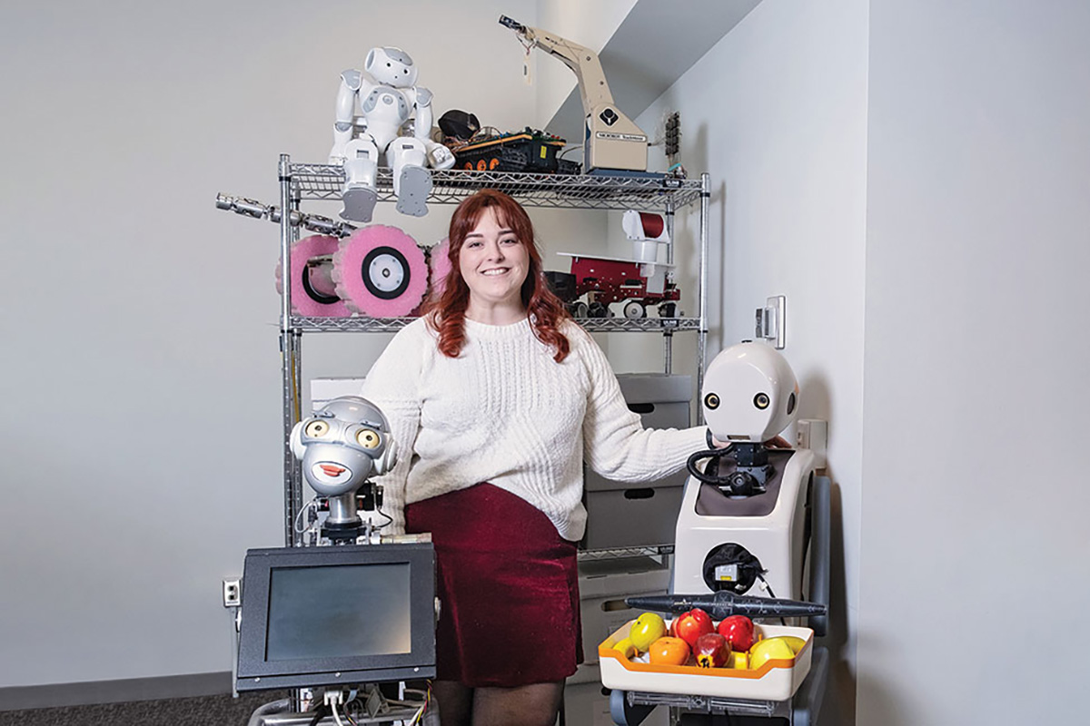 Kathleen Donahoe, robot archive processing archivist at Carnegie Mellon University (CMU), poses with a selection of robots in CMU's archive. Photo: Heather Mull