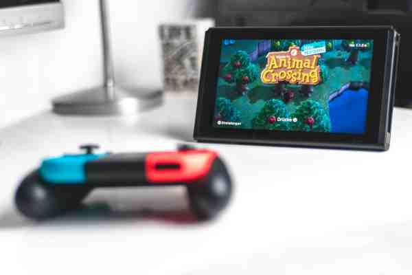 A Nintendo Switch and controller on a white table with Animal Crossing: New Horizons on the screen.