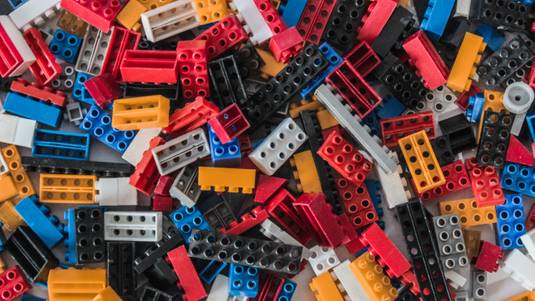 Assorted pile of rectangle and square Legos in blue, white, yellow, black, grey, and red. Fran Jacquier of Unsplash.