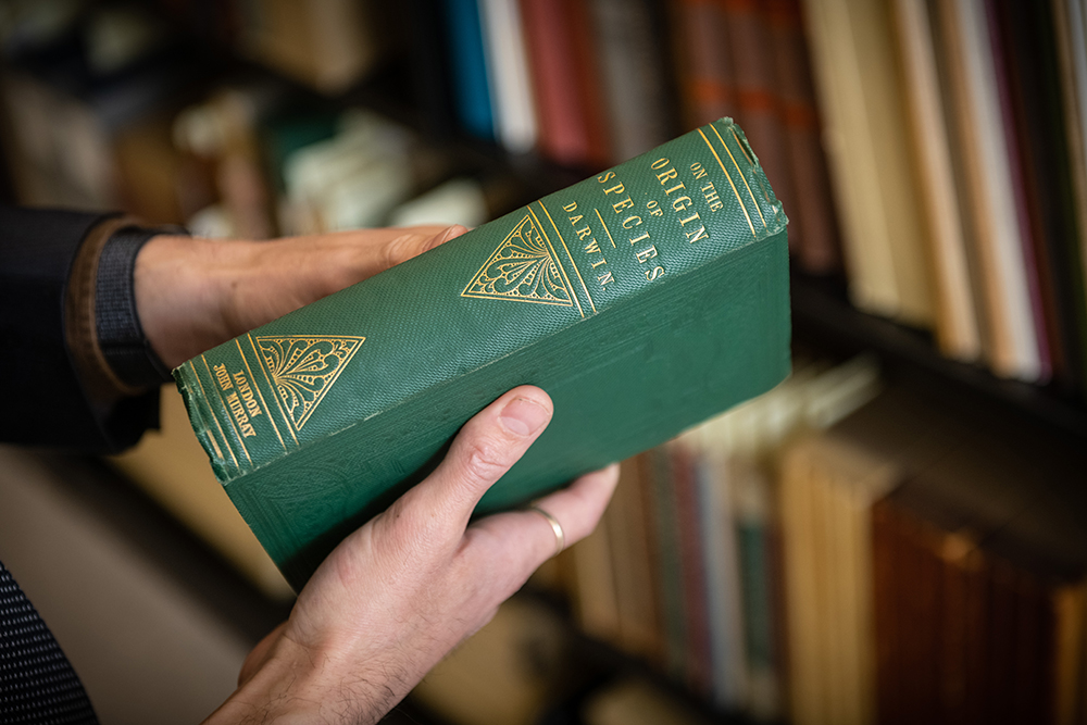 Image of Special Collections librarian holding a rare copy of On the Origin of Species.