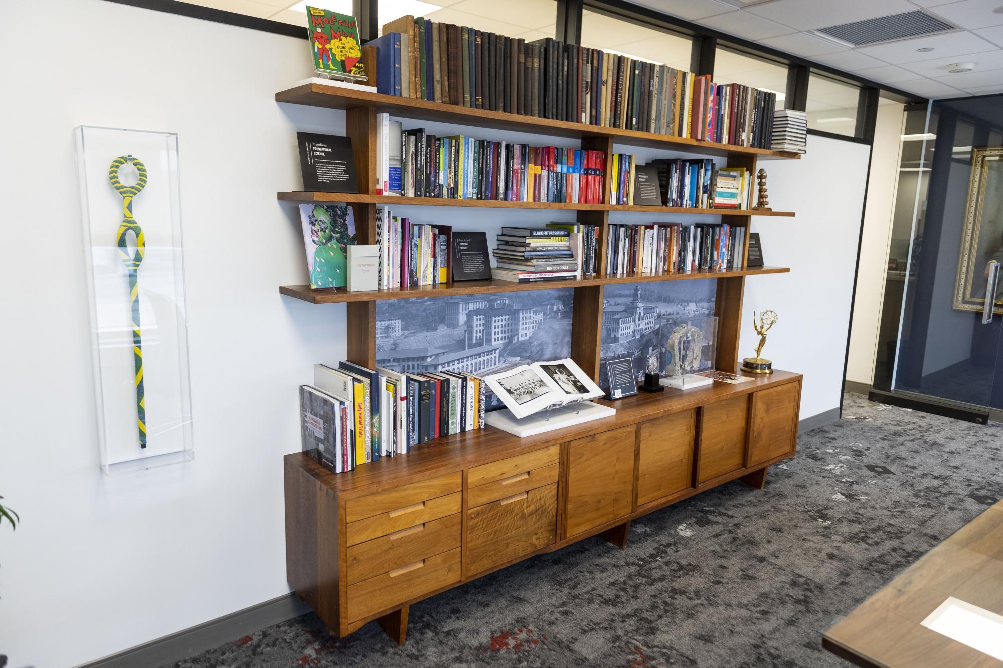 The bookshelf, designed by George Nakashima, is located in the Mellon Conference Room in President Jahanian’s office on the sixth floor of Warner Hall. The President’s Collection on display was curated by University Libraries and the University Archives. Objects in the display are on loan from the Archives.