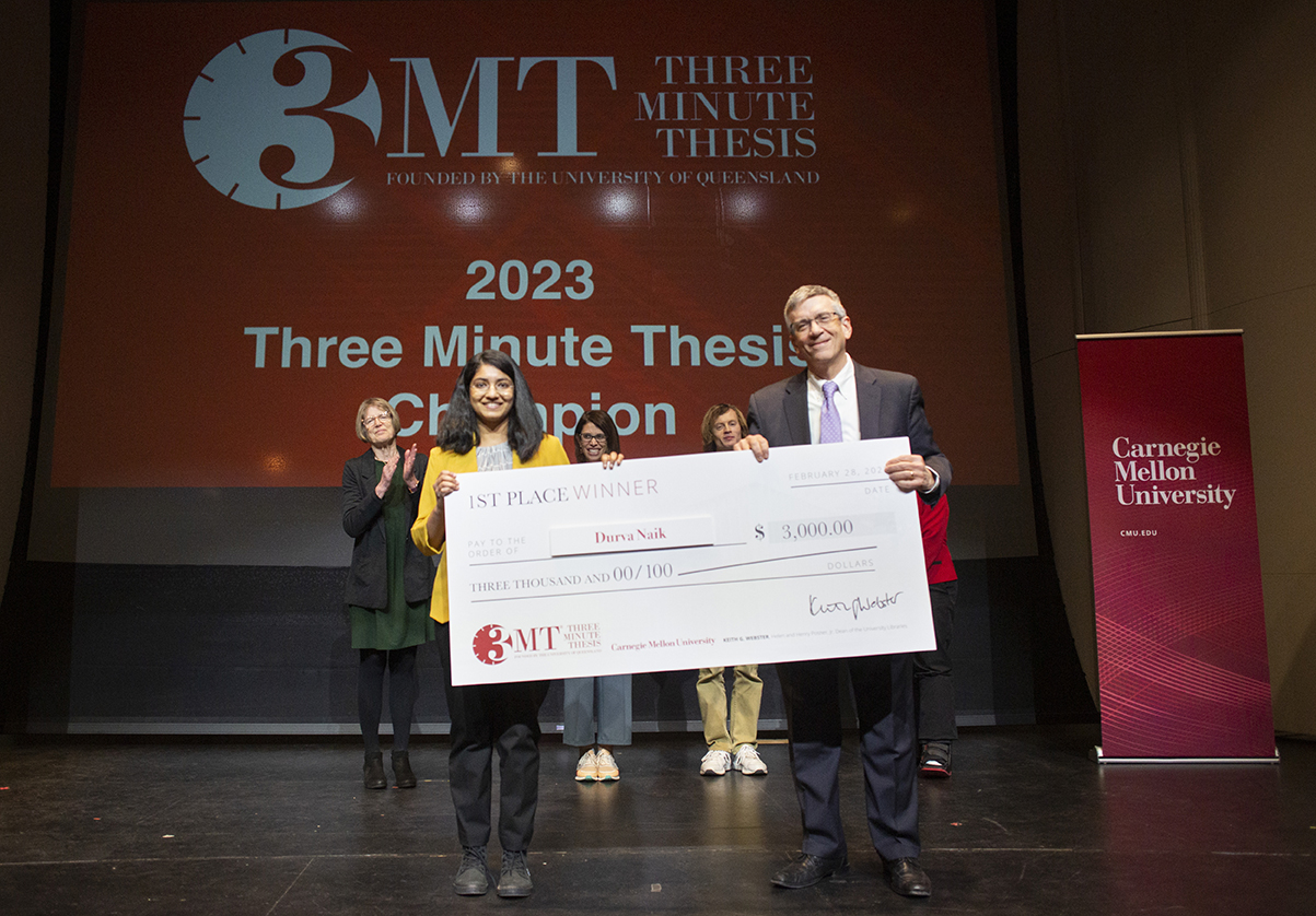 1st place winner, Durva Naik, is presented a check by Provost Jim Garrett.