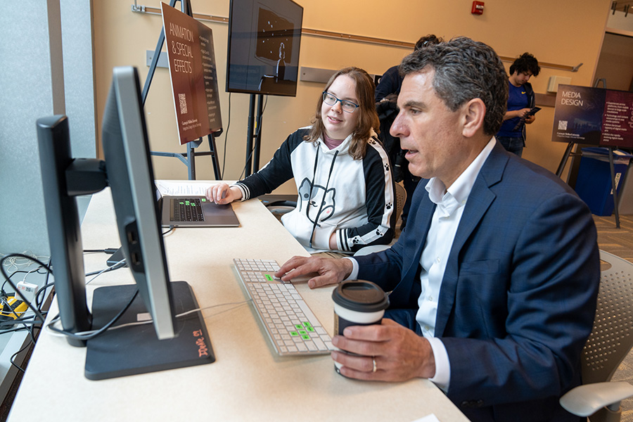 Biological Sciences junior Allison Wivagg instructs Associate Vice President of Advancement Matt Weinstein how to play Pass the Penguin, a new two-player game she and her teammates designed and produced.