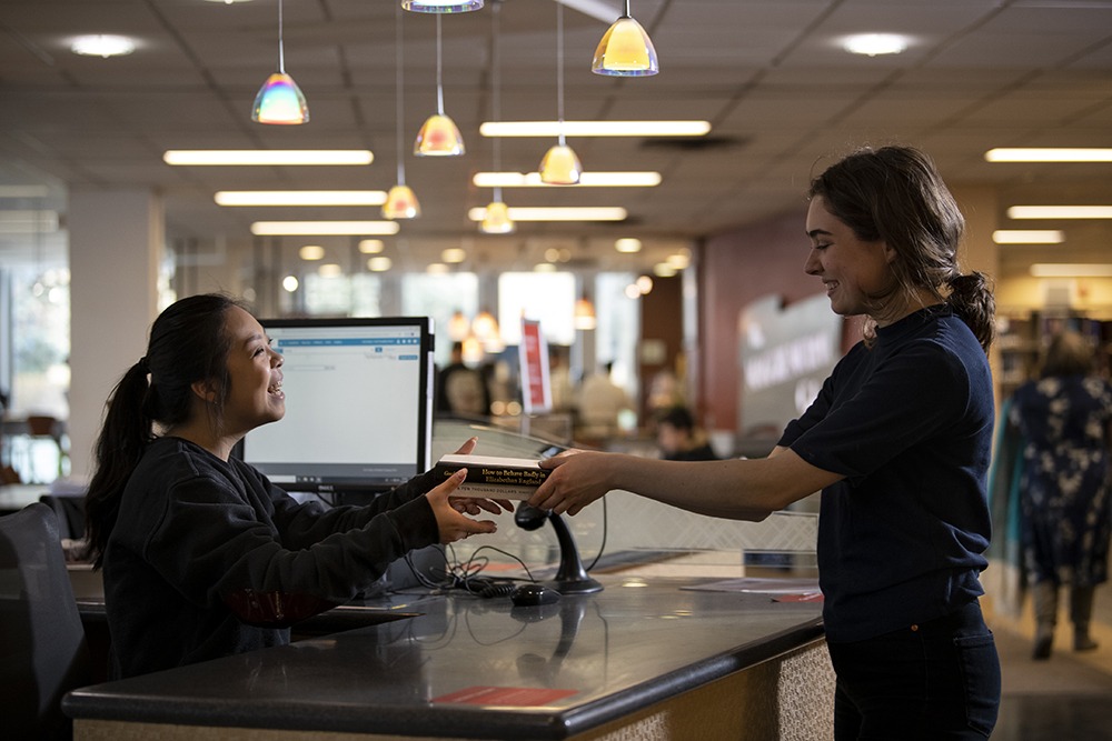 A guest gets books from the front desk at Hunt Library