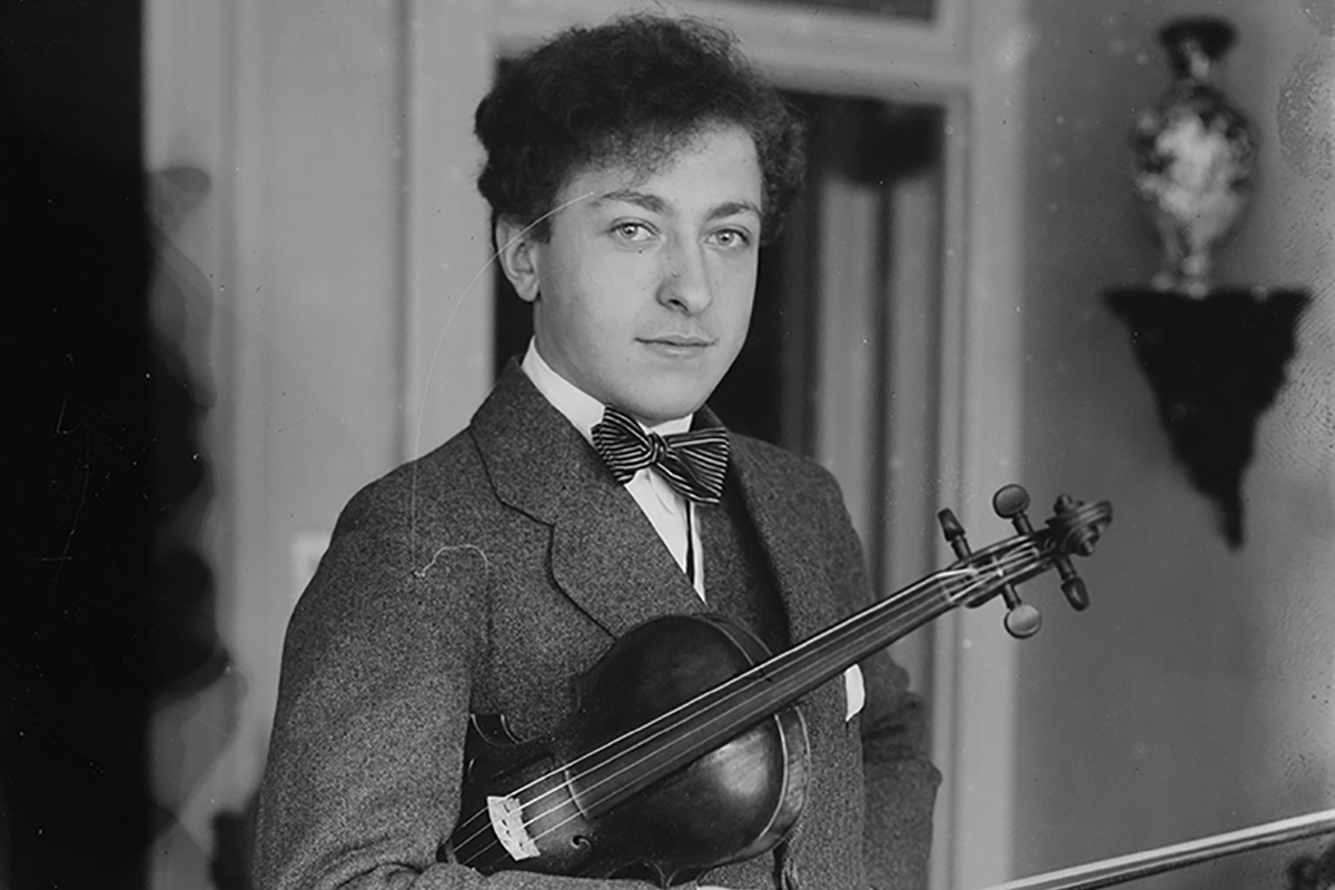 Jewish violinist Jascha Heifetz (1901-1987) with a violin standing by a piano. Courtesy of George Grantham Bain Collection, Library of Congress. 