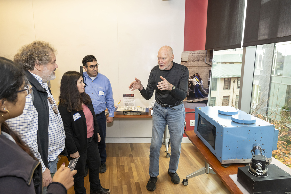 William “Red” Whittaker, Faculty Emeritus and founding director of the Field Robotics Center, speaks to a group including Bruce Eppinger (CIT 1986), Rachel Reinitz (CIT 1987), and Steve Berman (CIT 1991) about the blue sensor beside him. The sensor is an early laser scanner created by the Environmental Research Institute of Michigan.