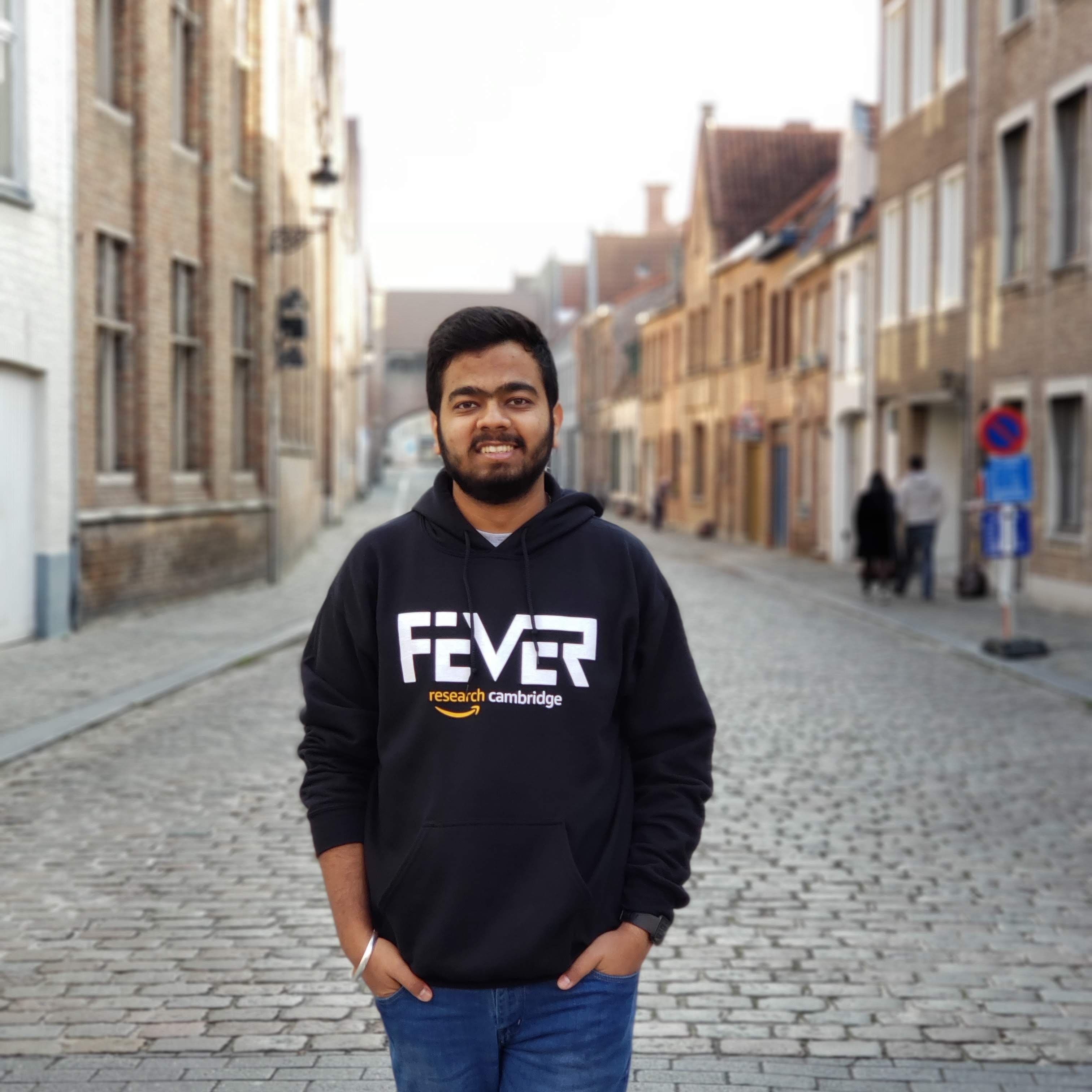 Divyansh stands smiling in front of buildings